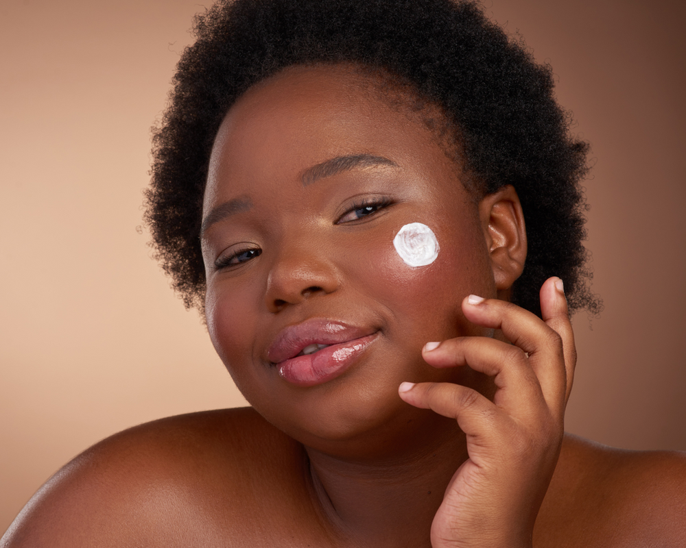 Fonte: Canva mulher negra feliz passando creme no rosto