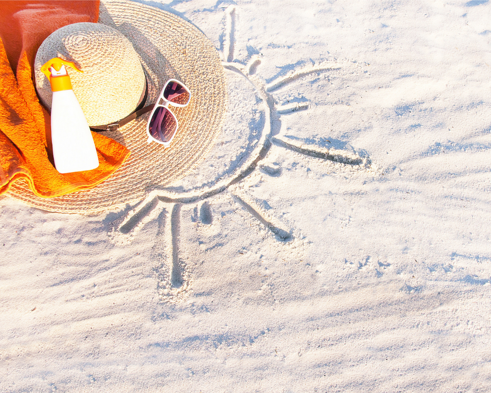 foto da areia da praia desenhado um sol com chapéu e óculos ao lado