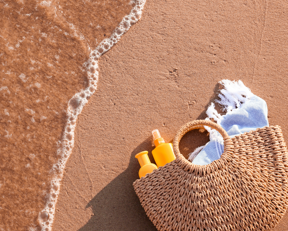 foto de uma bolsa de praia na areia da praia com protetor solar dentro