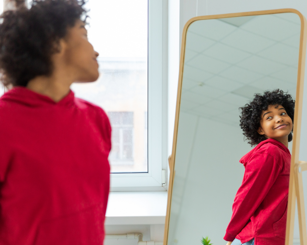 menina negra olhando para o espelho feliz